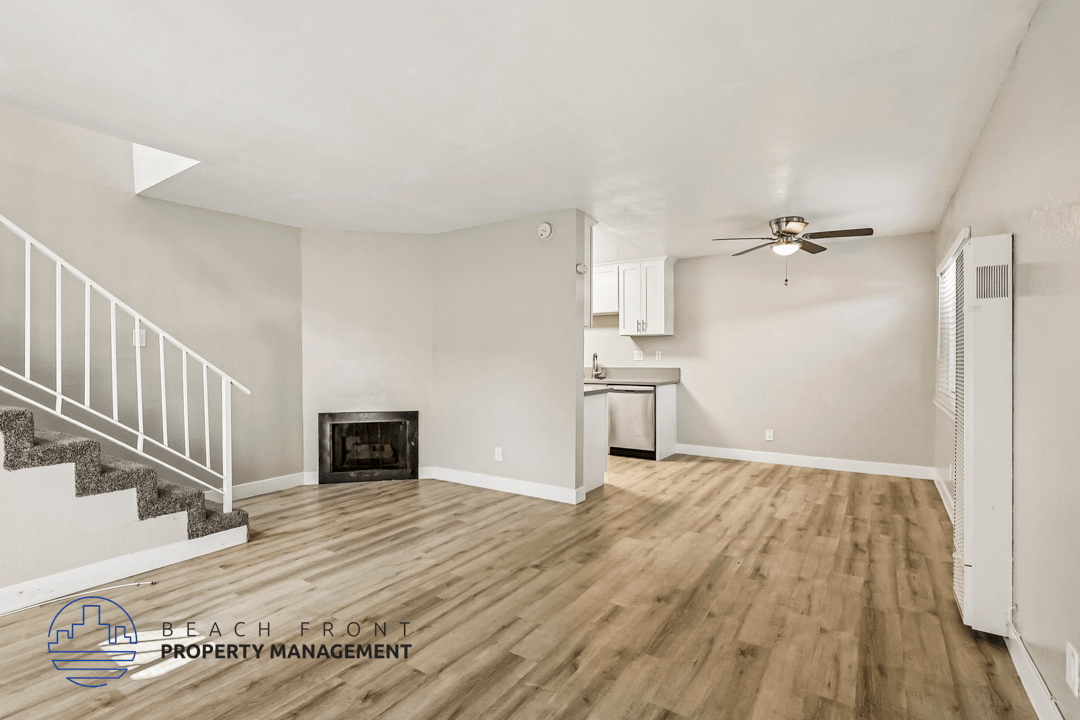 A spacious room with wooden flooring and a staircase leading to the upper level.